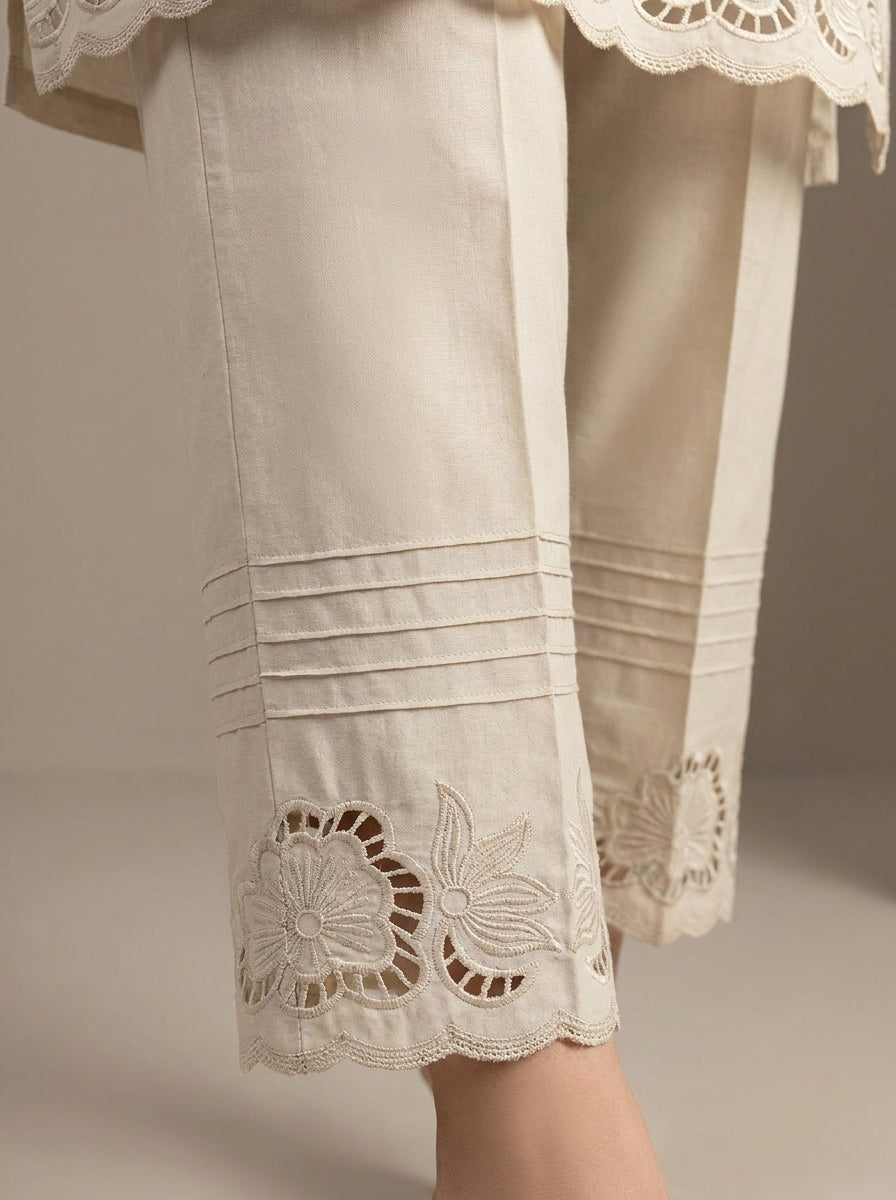 delicate cutwork floral embroidery pattern and pin-tuck pleats on off-white pants.