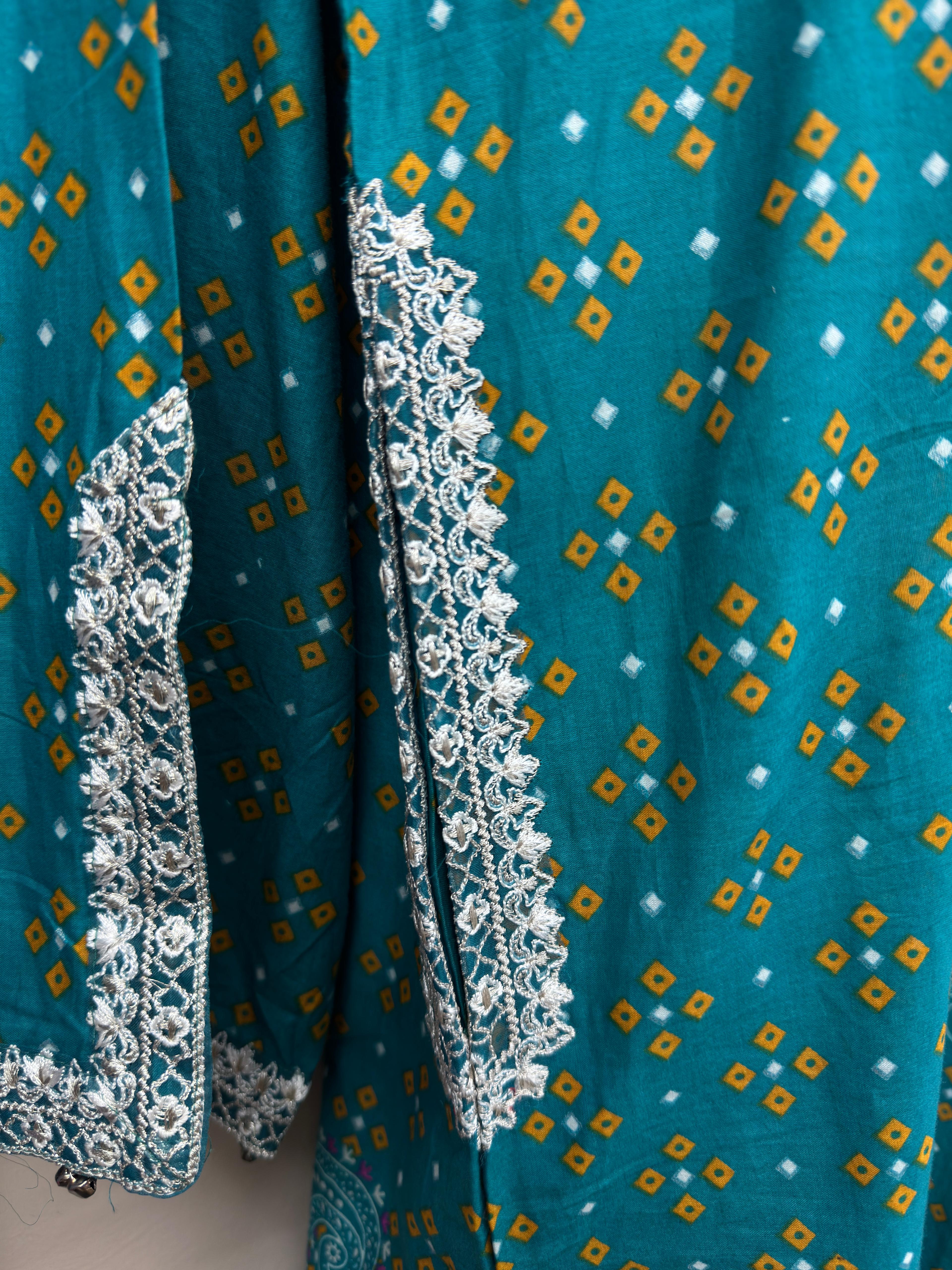 Teal fabric with white and gold patterns and lace trim